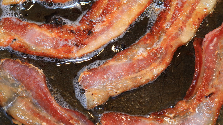 Bacon strips cooking in pan