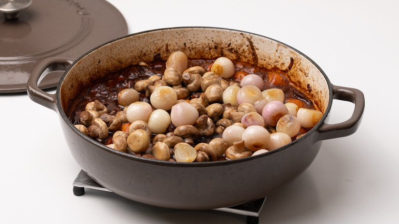 adding ingredients to beef bourguignon