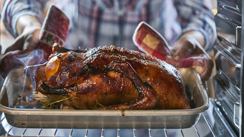 Cook pulling roast duck from oven