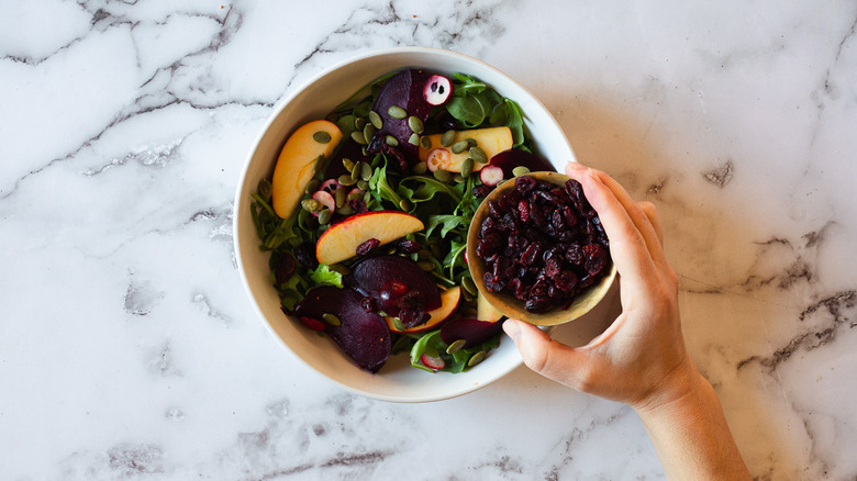 adding cranberries to salad