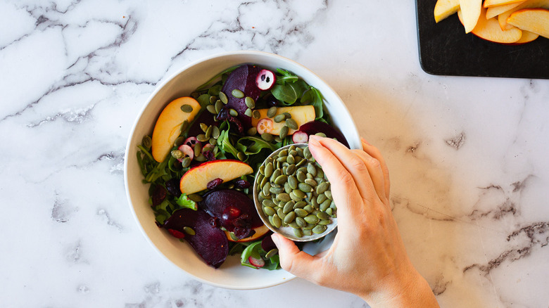 adding pumpkin seeds to salad