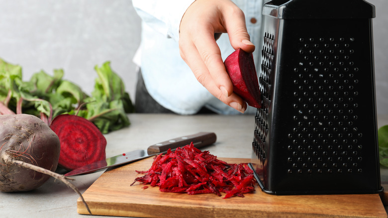 Person grating beets with a box grater 