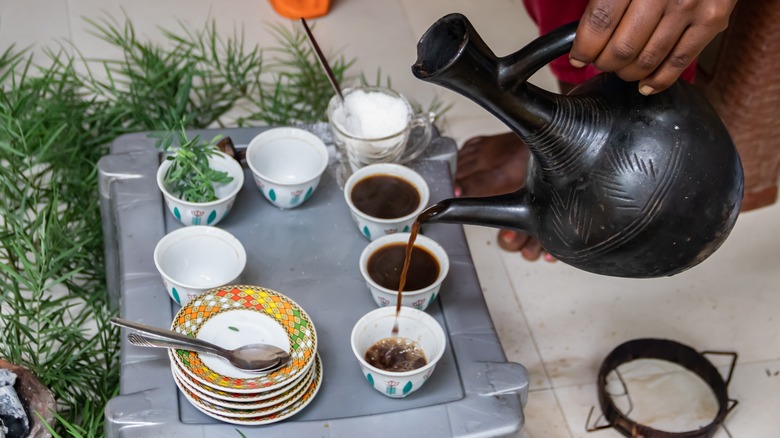 Person pouring coffee from a jebena