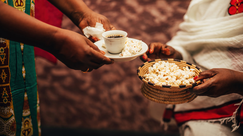 Person holding a tray of Ethiopian coffee and popcorn