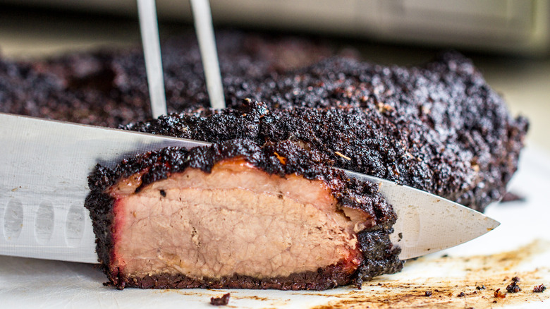 knife slicing through smoked brisket