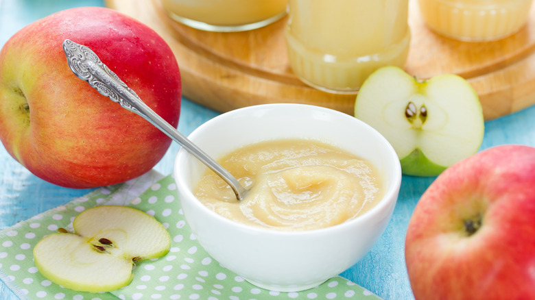 a bowl of applesauce surrounded by apples