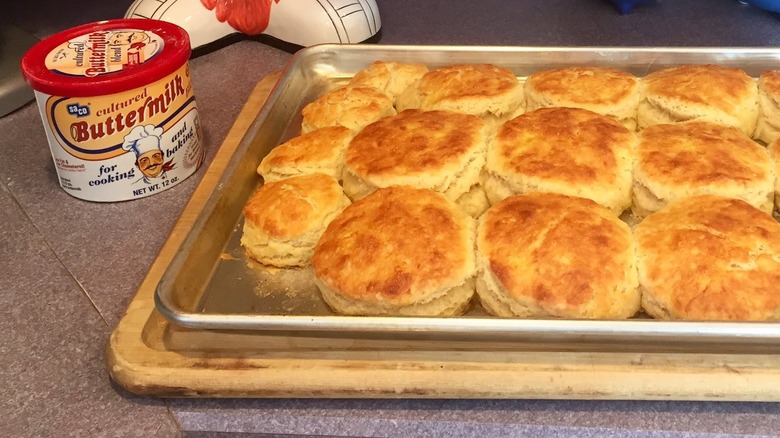 a sheet tray of biscuits next to a container of SACO buttermilk powder