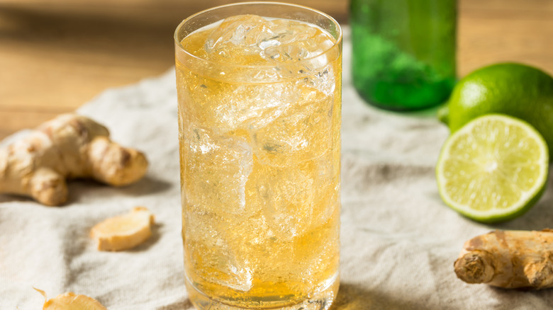 Glass of iced ginger ale with ginger root and limes