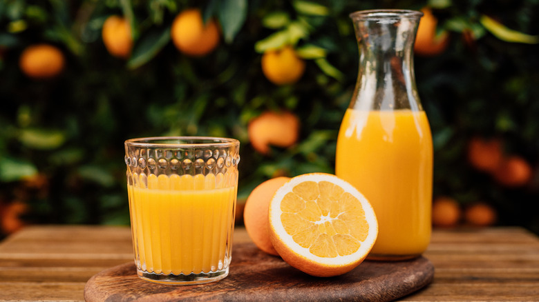 Glass and carafe of orange juice with halved orange