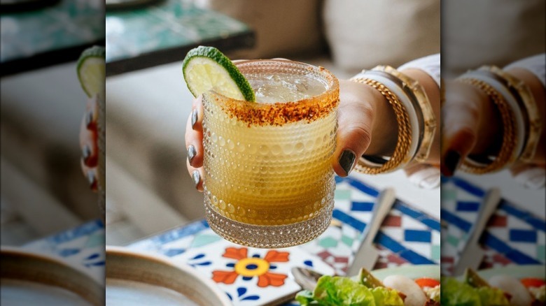 Hand holding a margarita with lime