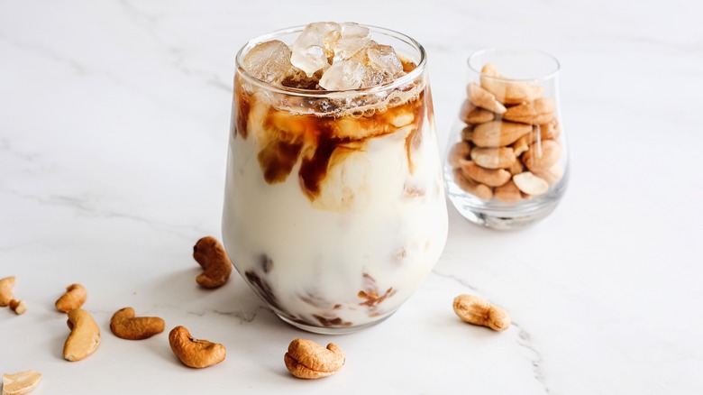 Iced coffee in glass next to jar of cashews