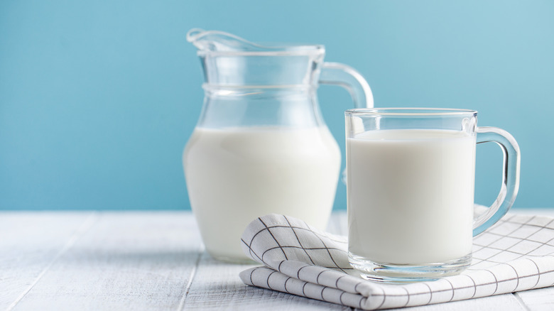 Pitcher of milk next to a glass mug of milk