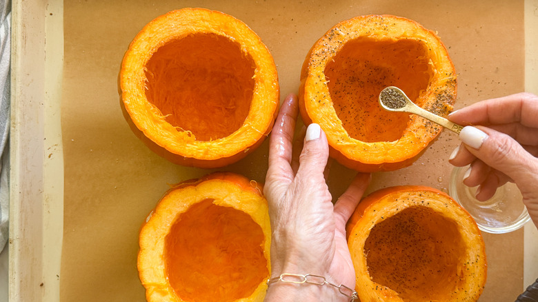 hand adding pepper to pumpkins