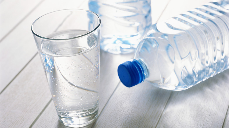 a glass of water next to bottles of water