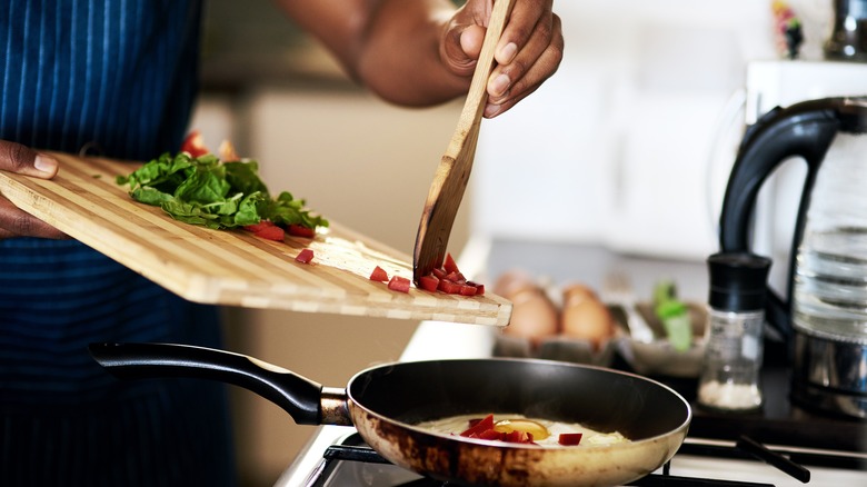 cook putting ingredients into pan