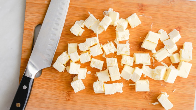 chopped butter cubes on cutting board with knife