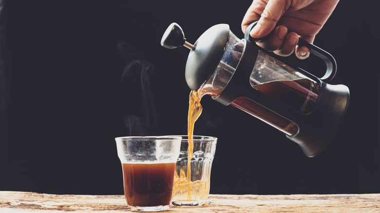 hands pour from a french press into glass