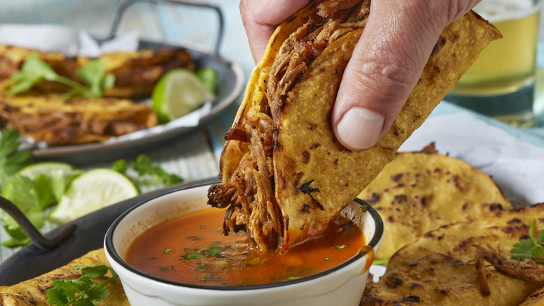 dipping birria taco in consomé