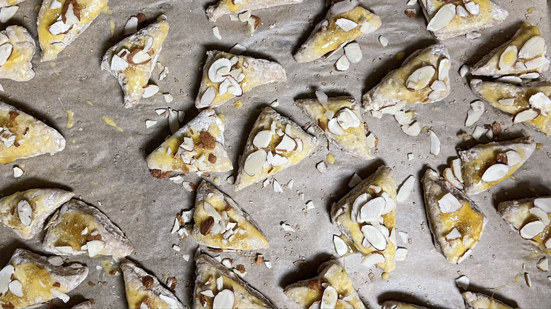 unbaked scones with sliced almonds on parchment-lined tray