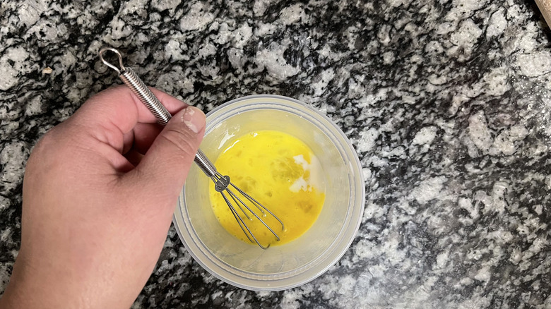 hand stirring egg in small bowl