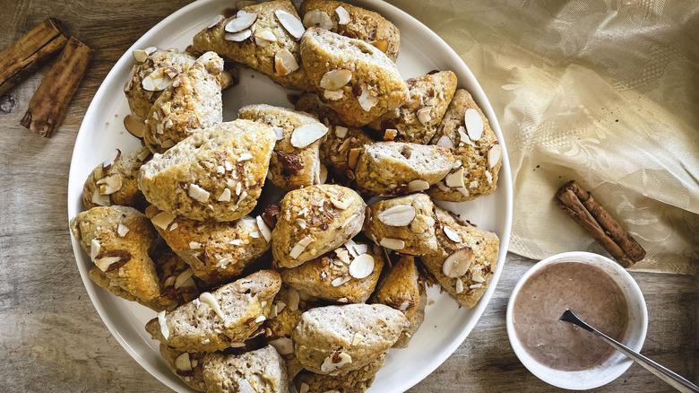 triangular scones with almonds on white plate with dipping sauce