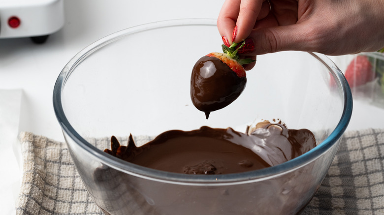 strawberry getting dipped in chocolate