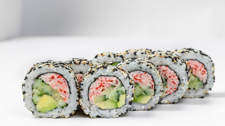 Crab, cucumber, and avocado sushi rolls coated in black and white sesame seeds