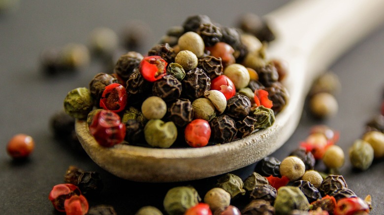 Close-up of a spoonful of red, green, and black peppercorns