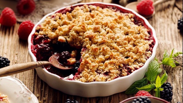 A spoon in a dish of black raspberry cobbler