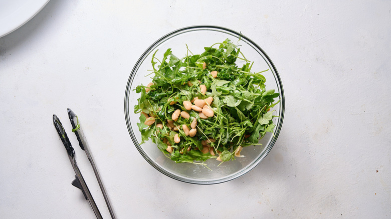tossing salad with dressing in bowl