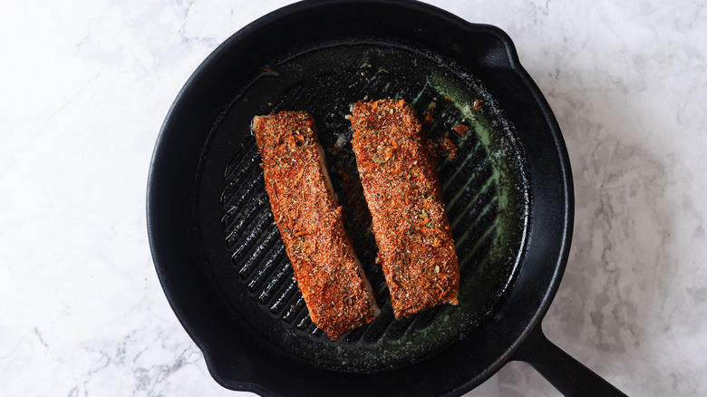 fish coated with spices in black skillet