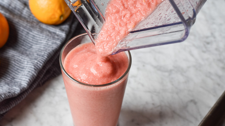 pouring blood orange smoothie into glass