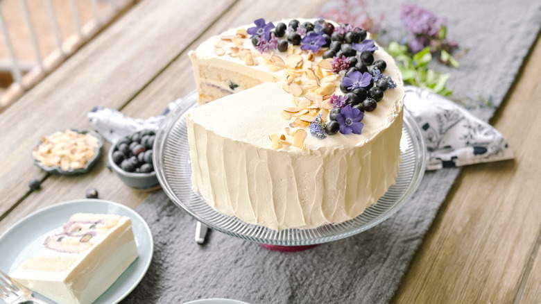 Blueberry and almond chantilly cake sliced on table with flowers