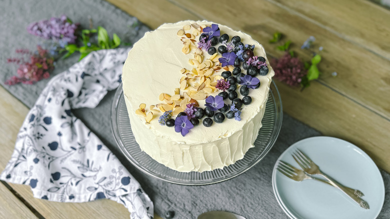 Blueberry and almond Chantilly cake on cake stand on table with fresh flowers