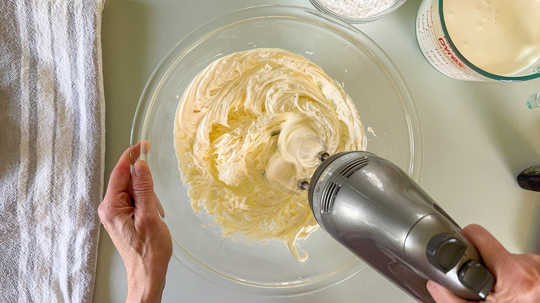 Beating mascarpone cheese in glass bowl with hand mixer