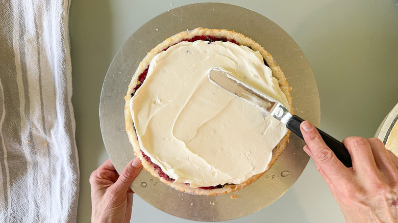 Spreading Chantilly cream on round cake layer with offset spatula