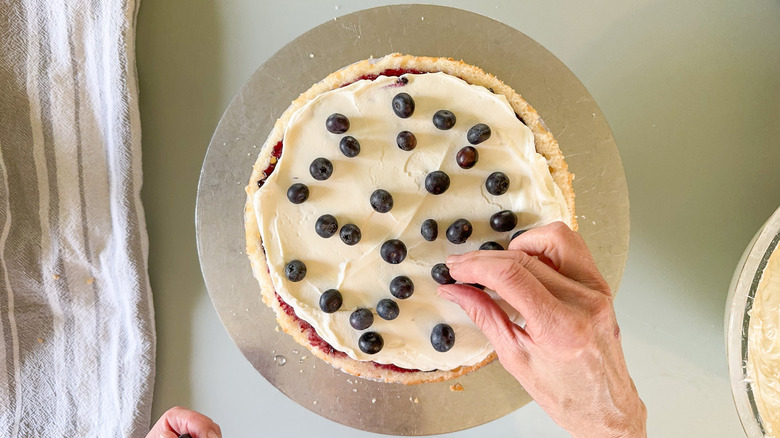 Adding blueberries to Chantilly cream cake