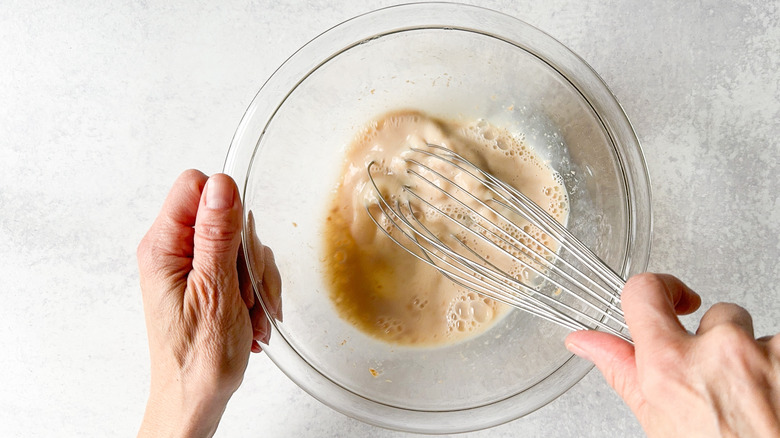 Whisking together egg whites, milk and extracts in glass bowl