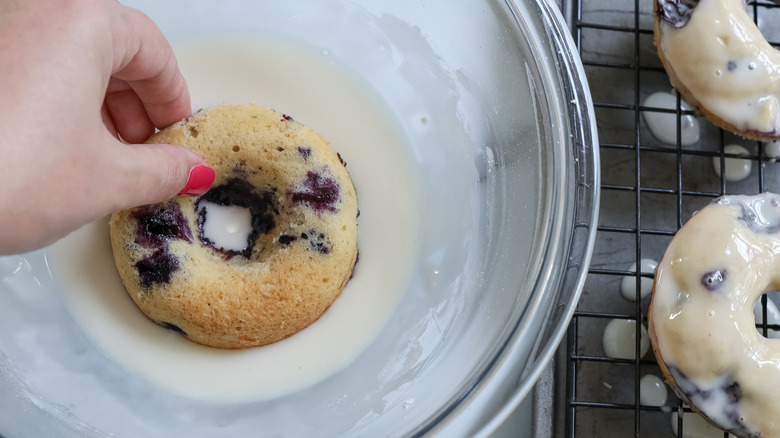 dipping blueberry donut in glaze