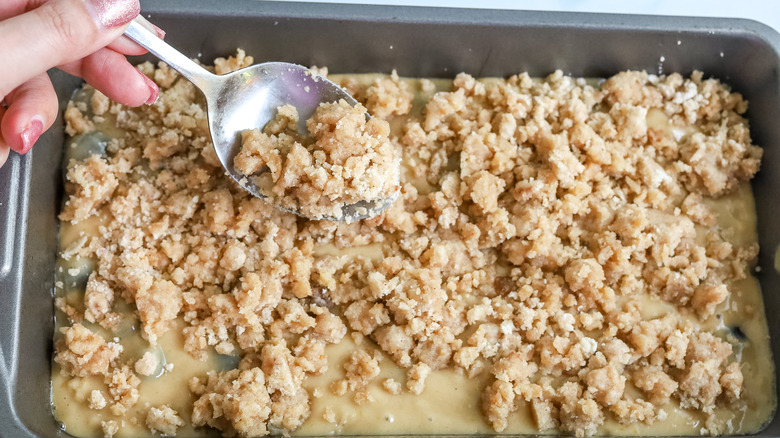 crumble topping being spooned over batter