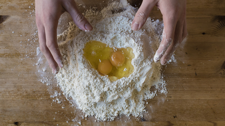 hands making pasta dough with eggs