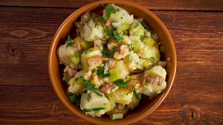 bowl of german style potato salad against wood counter top