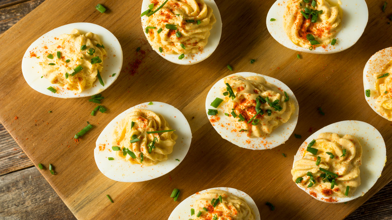 deviled eggs arranged on a rustic wood cutting board