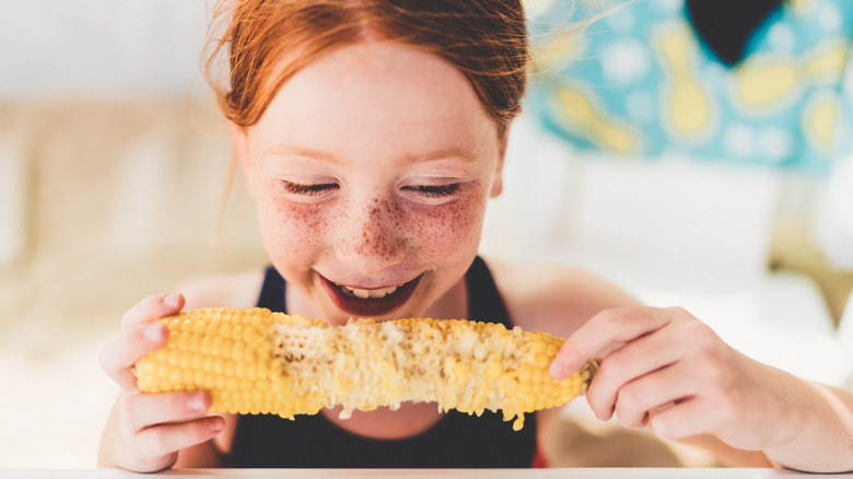 freckled girl eating corn