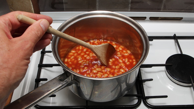 Hand stirring pot of baked beans 