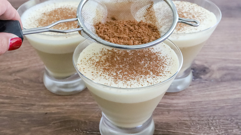 Cocoa powder being dusted onto boozy Irish coffee panna cotta