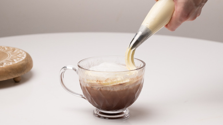 piping cream onto latte