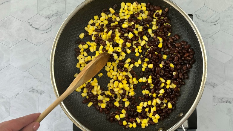 hand stirring corn and beans