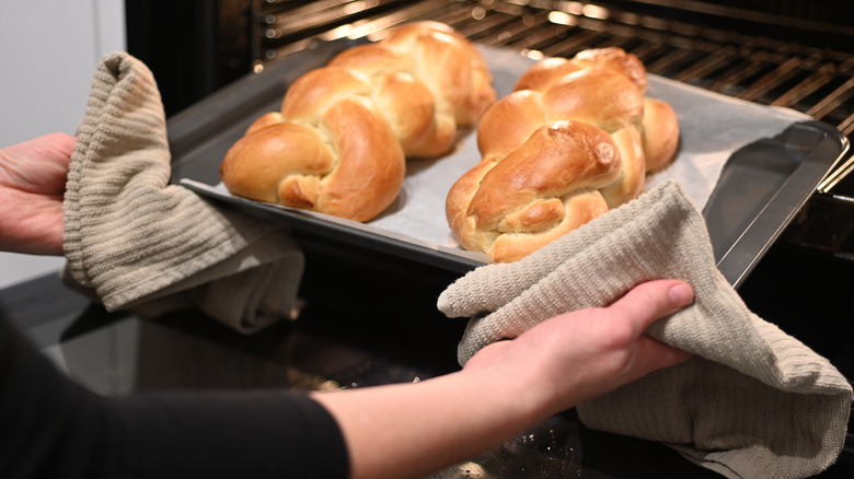 Hands removing tray of bread