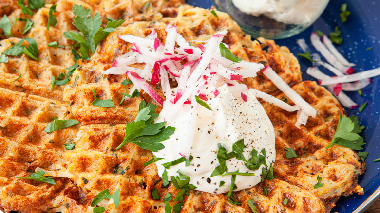 potato pancake waffles with creme fraiche and herbs on a blue plae